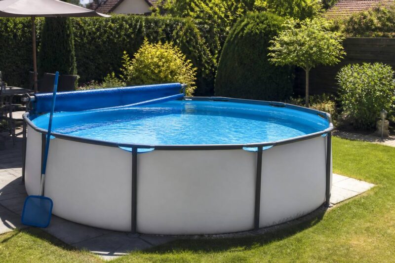 Schoon zwembad in een verzorgde tuin met onderhoudsspullen ernaast